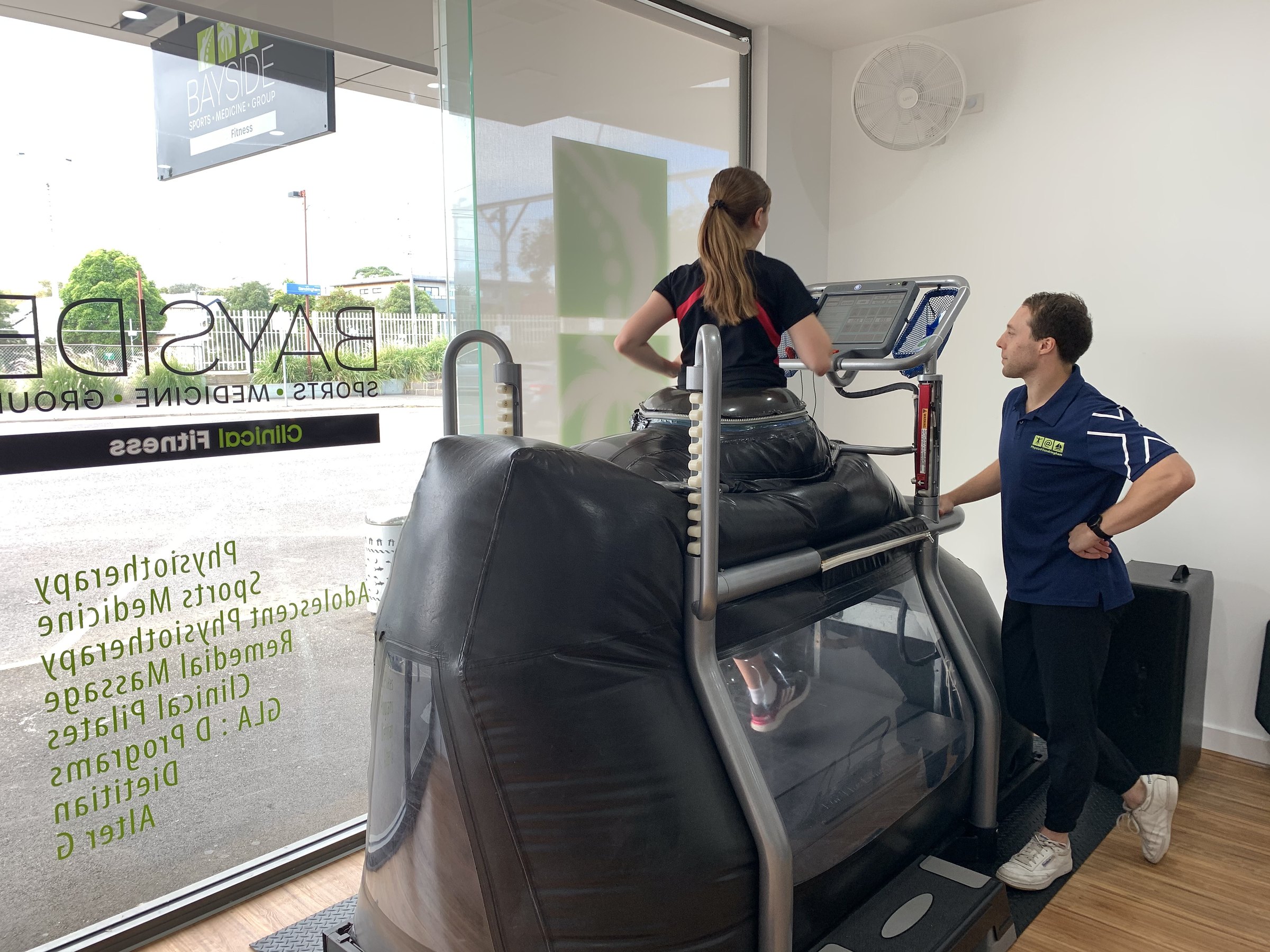 A patient on the AlterG anti-gravity treadmill with a physio beside her